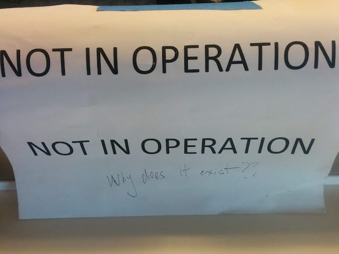 A photograph of a printed "NOT IN OPERATION" sign on which someone has graffitied "Why does it exist??"